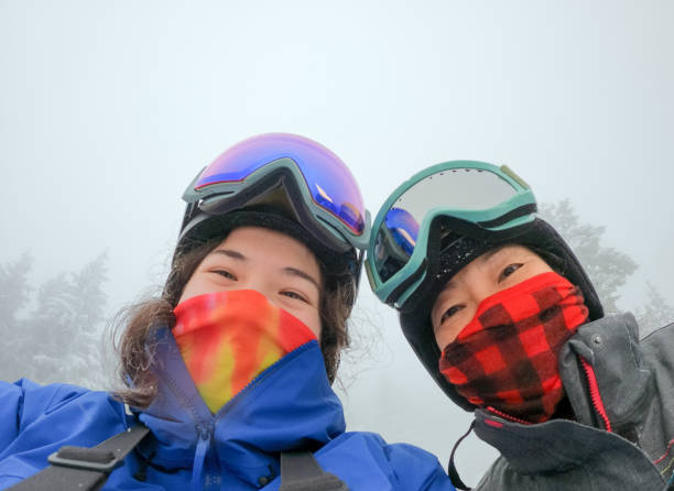 multi-ethnic daughter and asian mother wearing neck gaiters while skiing - mt seymour provincial park imagens e fotografias de stock
