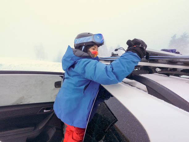 istock Multi-Ethnic Young Woman Locking Skis and Snowboard onto Roofrack 1299665954