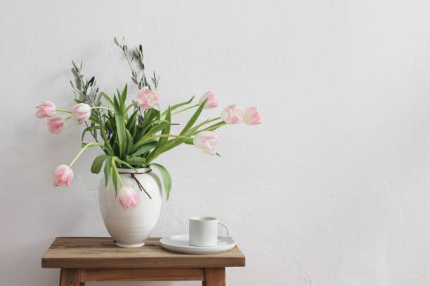 pascua romántica, escena de bodegón primaveral. taza de café y ramo floral en jarrón de cerámica blanca sobre banco de madera. foto de estilo femenino. flores de tulipanes rosados, ramas de olivo en la mesa. copiar espacio. - beautiful red pink wood fotografías e imágenes de stock