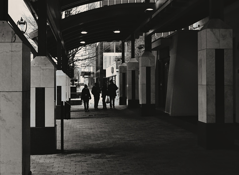 A shadowy view down a dark city sidewalk corridor in black and white. American culture. copy space.