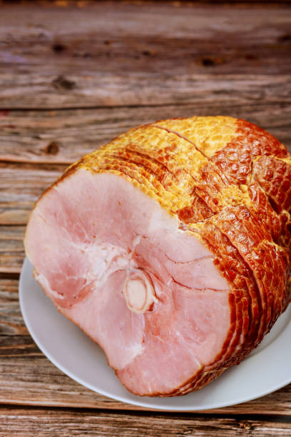 Sliced honey smoked ham on wooden table.