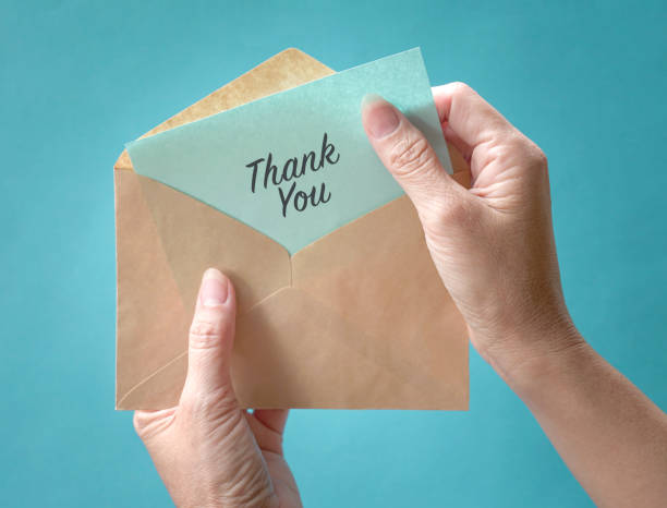 istock Woman open and look at thank you card or note inside a brown envelope. Close up view. 1299668996