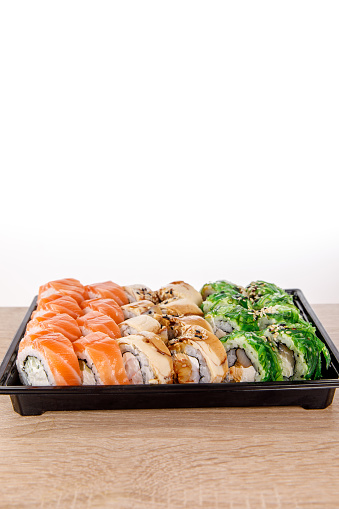 Sushi delivery. Different rolls in black plastic packaging Top view composing. Japanese and Asian food. Menu or delivery concept with space for text.