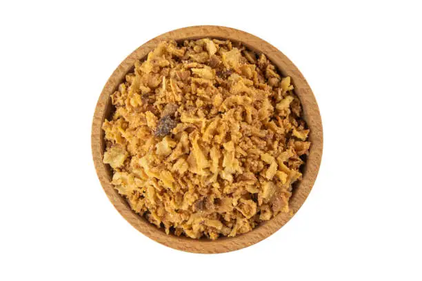 Crispy carmelized fried onion flakes in wooden bowl isolated on white background. Spices and food ingredients.