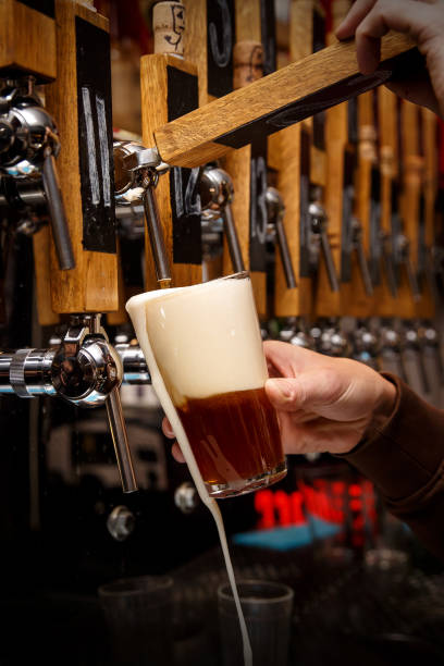 istock Barman hands pouring a dark beer in a glass 1299673422