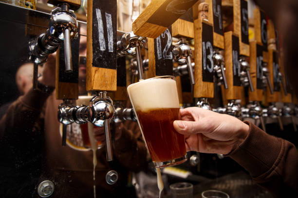 istock Hand of bartender pouring a red ale from tap. 1299673429