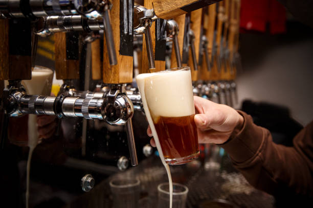 istock Hand of bartender pouring a red ale from tap. 1299673434