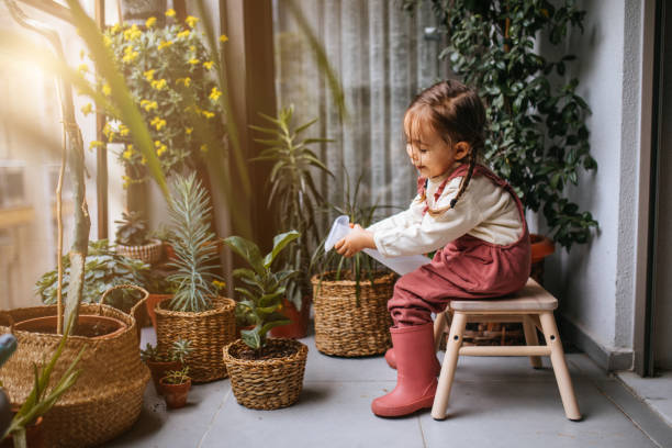istock Little girl watering houseplants 1299673763