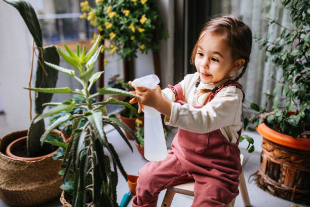 istock Little girl watering houseplants 1299674672
