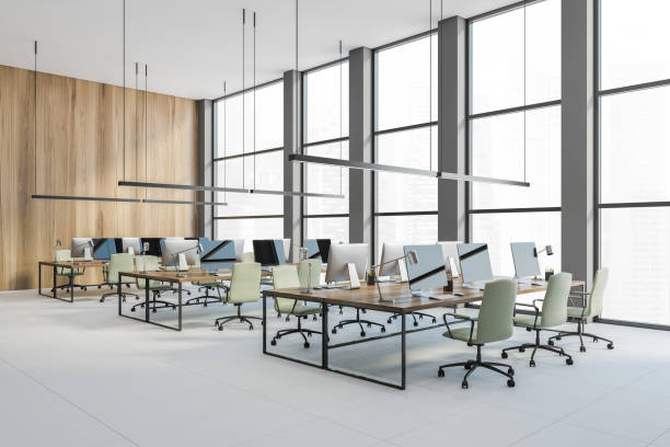 istock Open space office with green chairs and computers on the wooden table, no people 1299675799