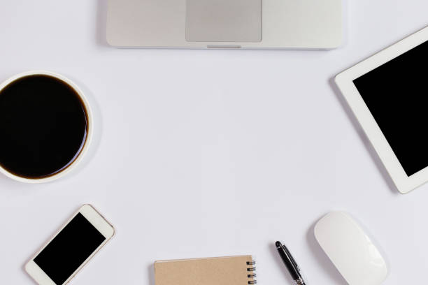 istock White Office desk table with laptop,smartphone and coffee cup and accessories. Business desk with a keyboard, mouse and pen on white table. Top view of workplace 1299676449