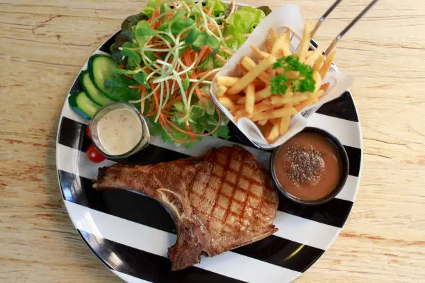 Top View Grilled steaks and vegetable salad. Steak porkchop black pepper.