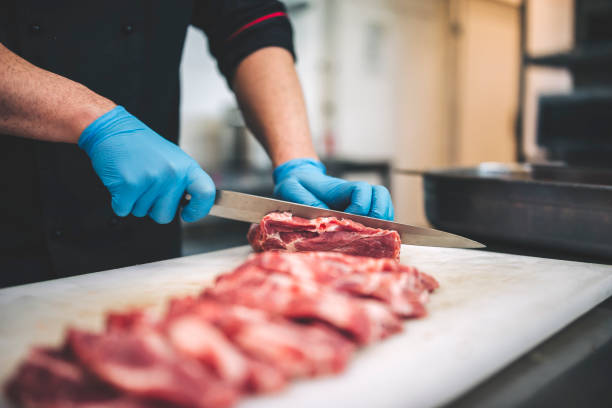 istock Male butcher cut raw meat with sharp knife in restaurants kitchen 1299679310