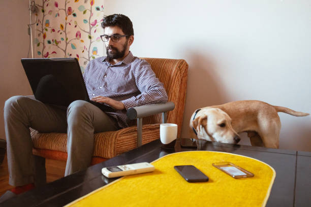 istock Man working on laptop at home, his pet dog is next to him 1299679563