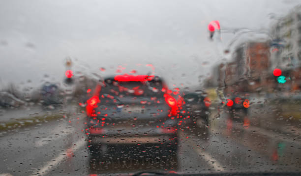 istock Driving car in rain bad weather droplets on windshield blurry image 1299680858