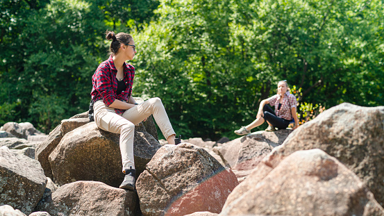 Teenage girls explore boulderfield in Poconos, Pennsylvania, USA, on a summer sunny day.