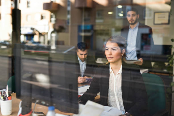 people working in an office seen through the window in a business company - common serious couple men imagens e fotografias de stock