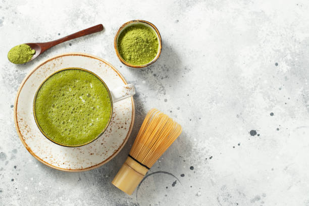 istock Matcha green tea latte in a cup with cream on a light concrete background. Top view with copy space 1299691075