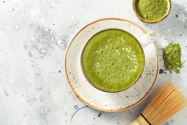 istock Matcha green tea latte in a cup with cream on a light concrete background. Top view with copy space 1299691086