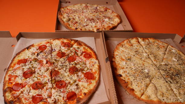 istock Close up of large pizzas in box on orange background. Appetizing pizzas with different ingredients 1299691889
