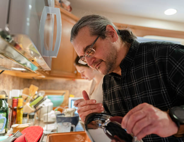 istock Middle aged man checking the soup that is in the pot on the stove. 1299691937