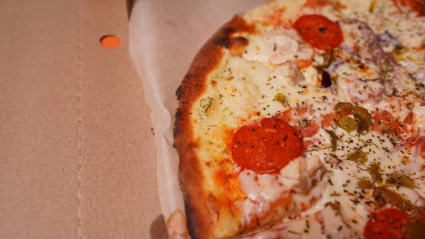 istock Close up of burnt pizza with different ingredients in box. Appetizing pizza with burnt edge 1299692004