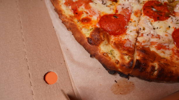 istock Close up of burnt pizza with different ingredients in box. Appetizing pizza with burnt edge 1299692012