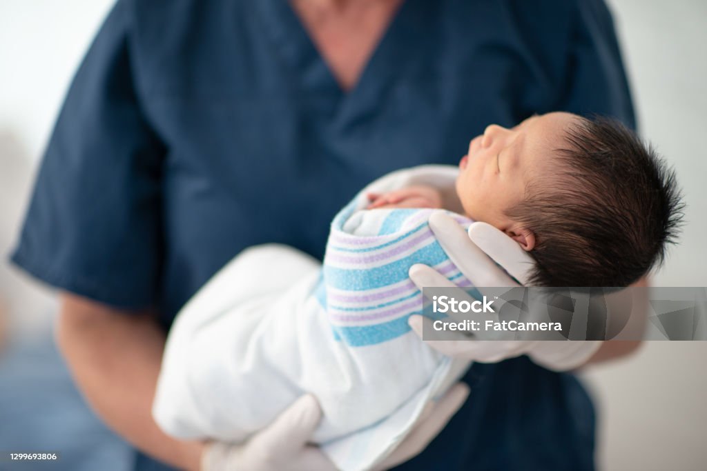 A new life A female nurse of is holding a newborn baby at the hospital. They baby is sleeping. Newborn Stock Photo