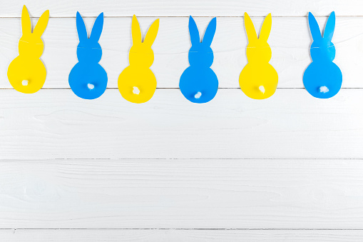Easter DIY decoration. The garland of blue and yellow paper rabbit.