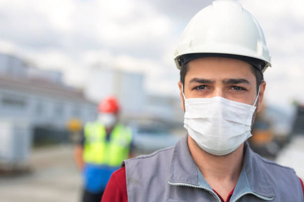istock The worker (staff, engineer) protects himself from covid-19 (coronavirus) with a protective mask in the construction site. 1299702337