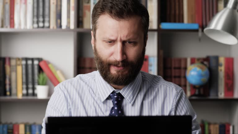 Man drinking alcohol. Bearded man at workplace pours whiskey brandy bourbon tape into glass and drinks. Depression, alcohol addiction, alcoholic, hangover, celebration concept. Close-up view