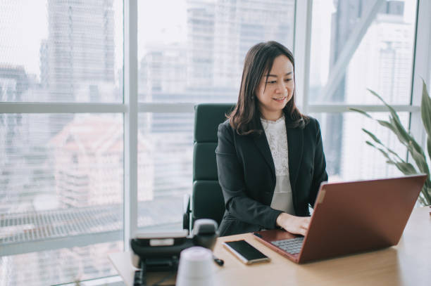 istock asian chinese beautiful female manager working using her laptop typing in the office 1299703388