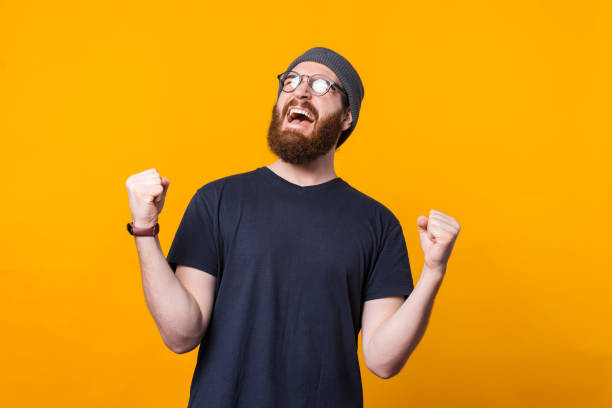 istock A young hipster with beard is screaming of happiness holding his both hands up 1299705897