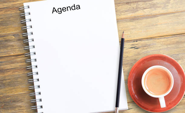 istock Notepad or notebook with pencil and cup of coffee on brown wood table background 1299707908