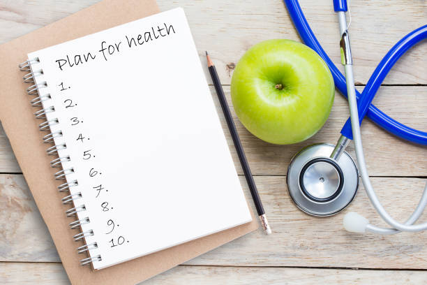 istock Blank paper notebook and blue stethoscope on brown wooden table background. 1299708045