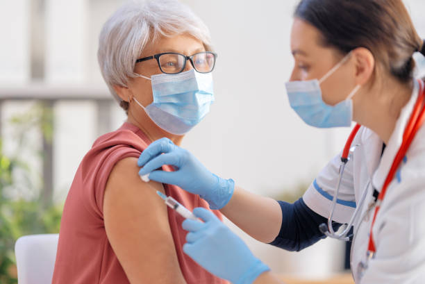 docteur vaccinant une femme âgée - syringe injecting vaccination healthcare and medicine photos et images de collection