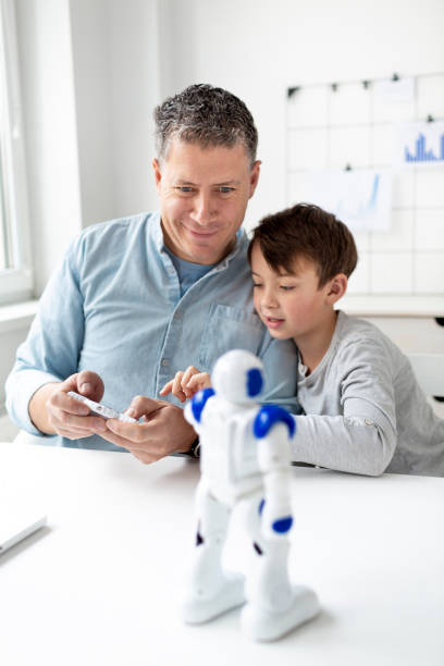 istock Father and son have fun together playing with a robot. 1299712915