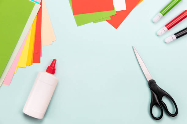 Top view over paper cut tools, scissors, cutter, cutting mat, and crafted paper objects. DIY trendy project concept. Flat lay