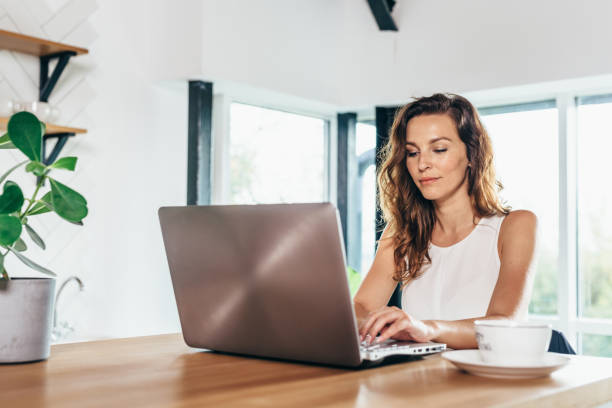 istock Woman is sitting at the kitchen table with laptop 1299719426