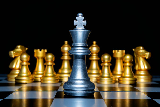 istock Chess leadership concept with silver and gold chess pieces isolated on black background 1299719545