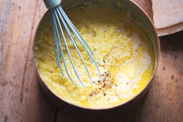 Cooked polenta dish, with parmesan, butter, salt and pepper . Polenta is made when cornmeal is boiled in water and chicken stock. stock photo