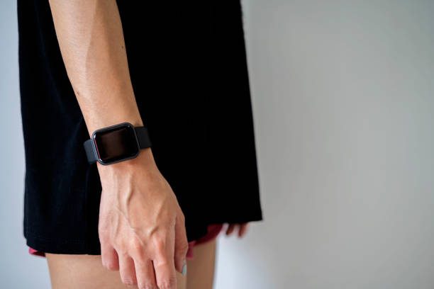 istock Cropped view of girl using smartwatch with blank screen on gray wall 1299723203