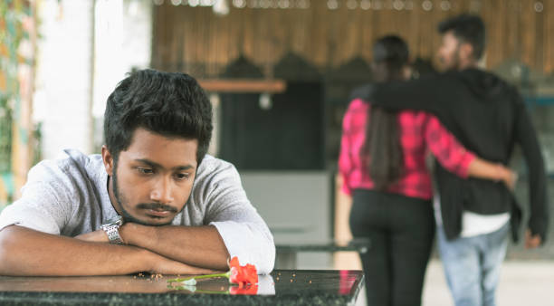 Sad young man seeing red rose during valentines day due to broken or betrayed relationship from his girlfriend.