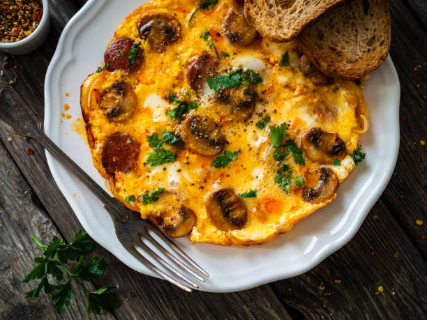 istock Continental breakfast -  scrambled eggs with sausages, champignons and toasts on wooden table 1299725998