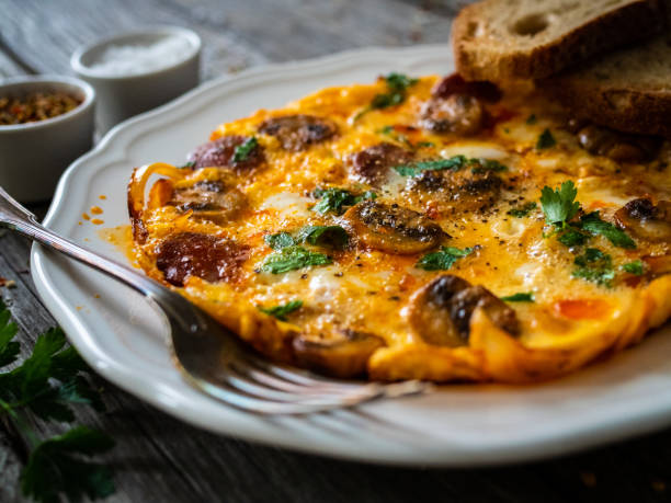 istock Continental breakfast -  scrambled eggs with sausages, champignons and toasts on wooden table 1299726043