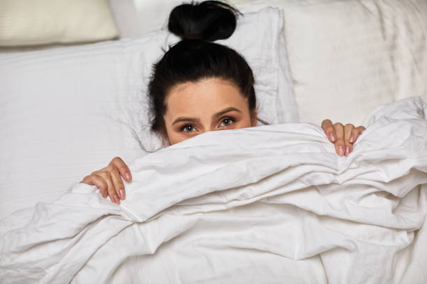 istock woman is lying in bed and hiding under blanket 1299726062