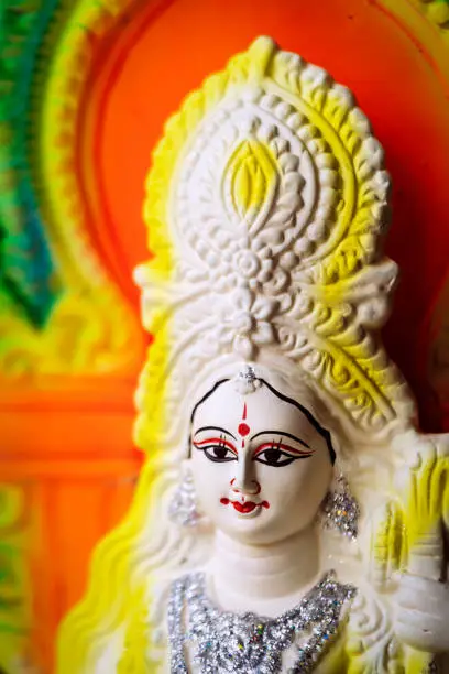 Idol of Goddess Saraswati painted in white and yellow colour on Basant panchami utsav. Swaraswati is a God of knowledge, music, art, wisdom and learning. Hindu Puja Background.