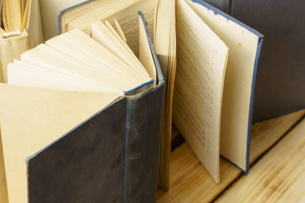 istock Open old hardback books stand on a wooden background. Science and education. 1299727953