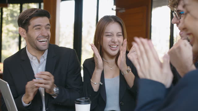 4k slow motion, multi-ethnic group of young business man and woman cheering and celebrating their success by clapping and giving high five to each other.