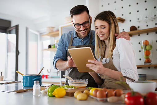 Happy couple enjoys and having fun preparing healthy meal together at home kitchen.
